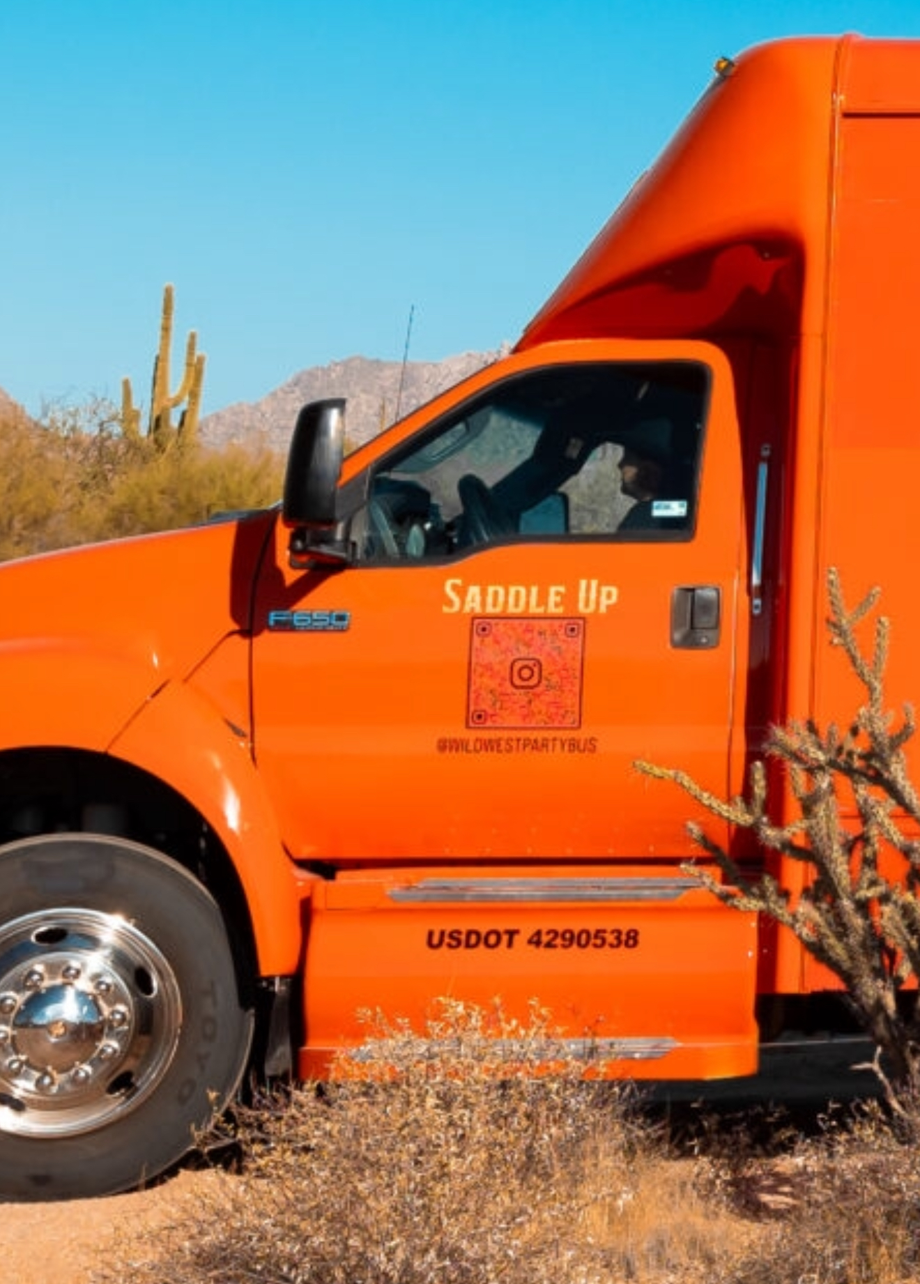Close view of the bus cab door showing the Saddle Up decal and USDOT 4290538