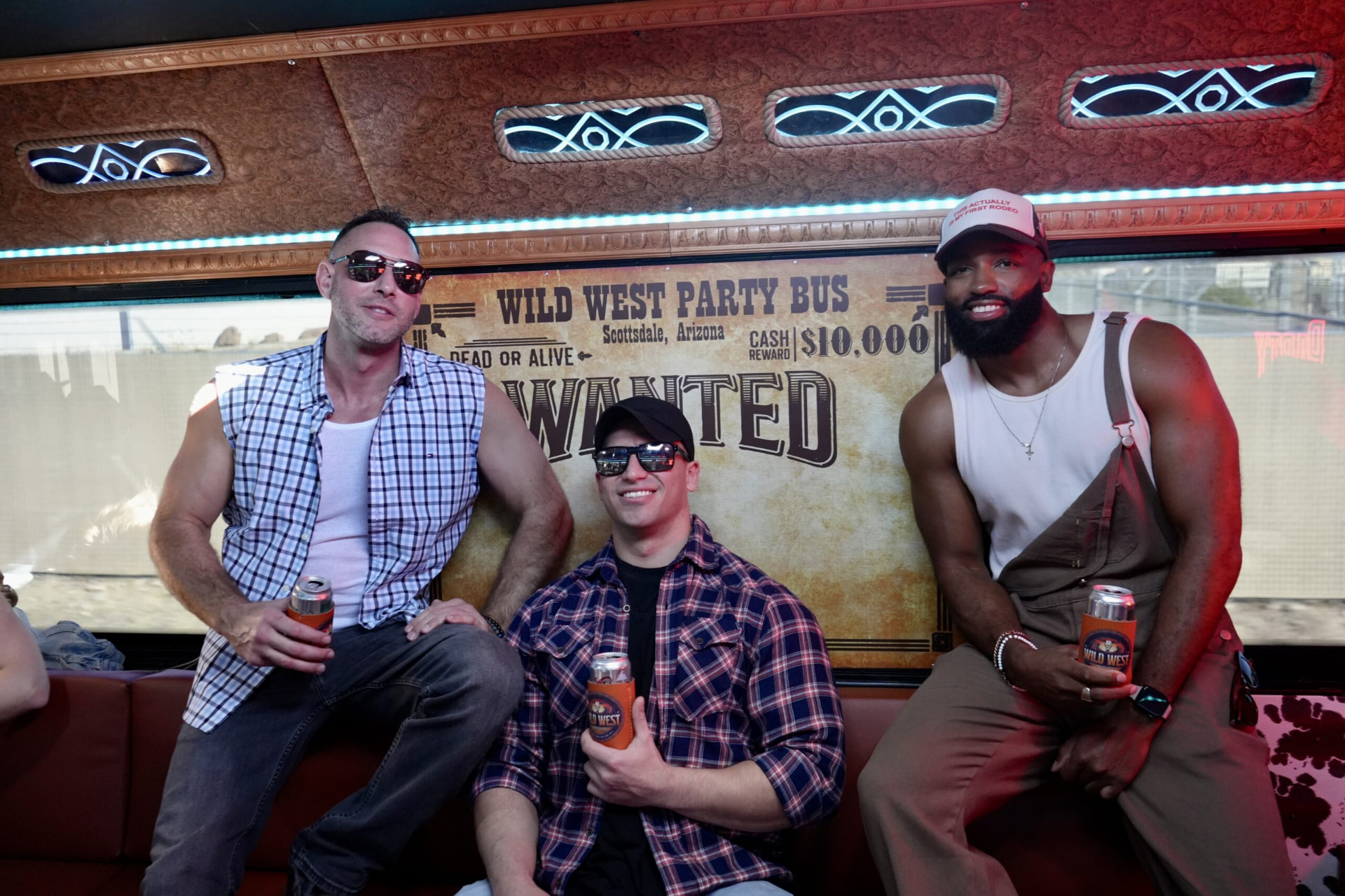 Three guests celebrating on board in front of the Wild West Party Bus wanted poster